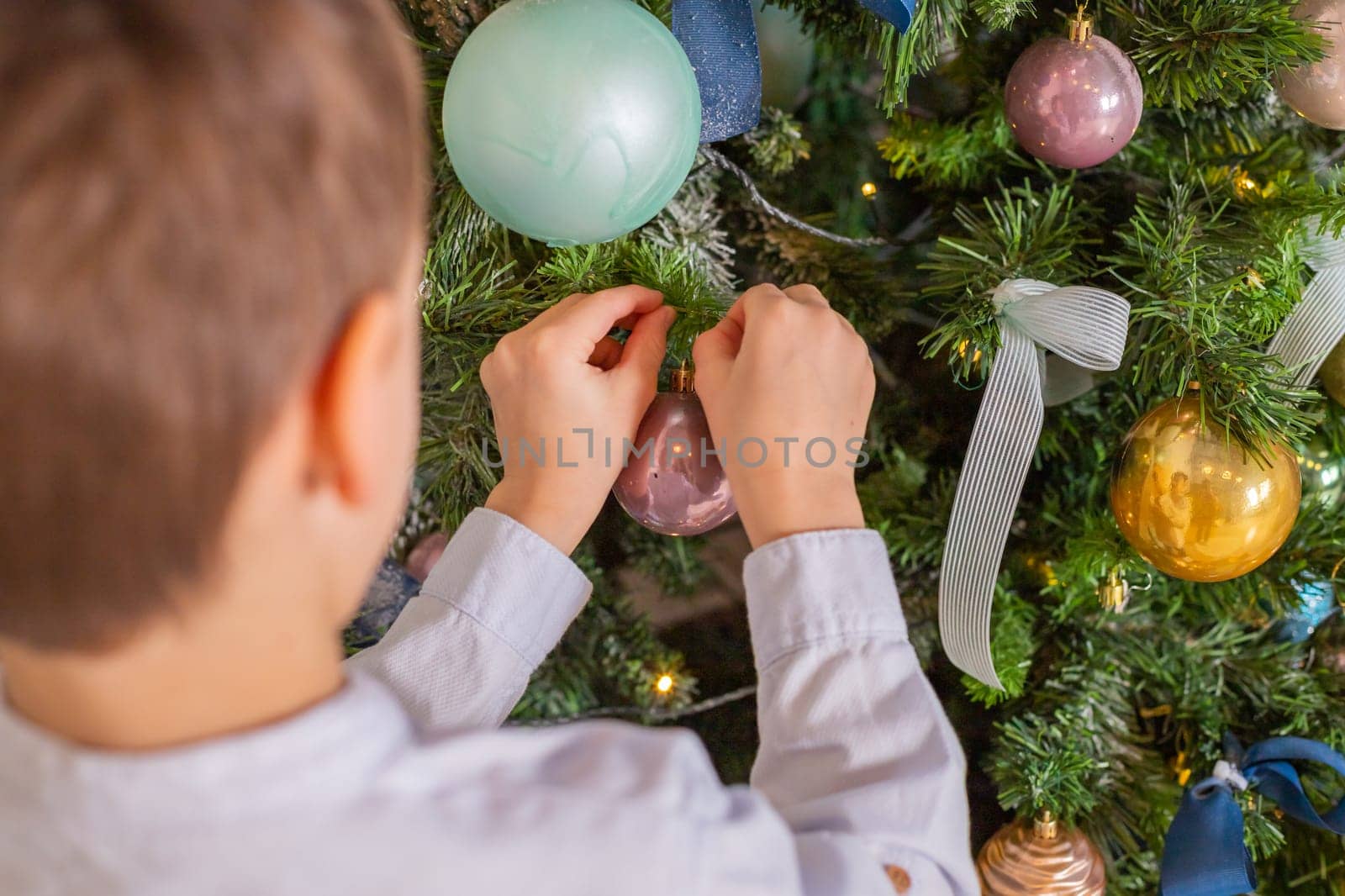 Hands mom and son decorate Christmas tree. Happy New Year and Merry Christmas. Family decorating a Christmas tree with a toy.