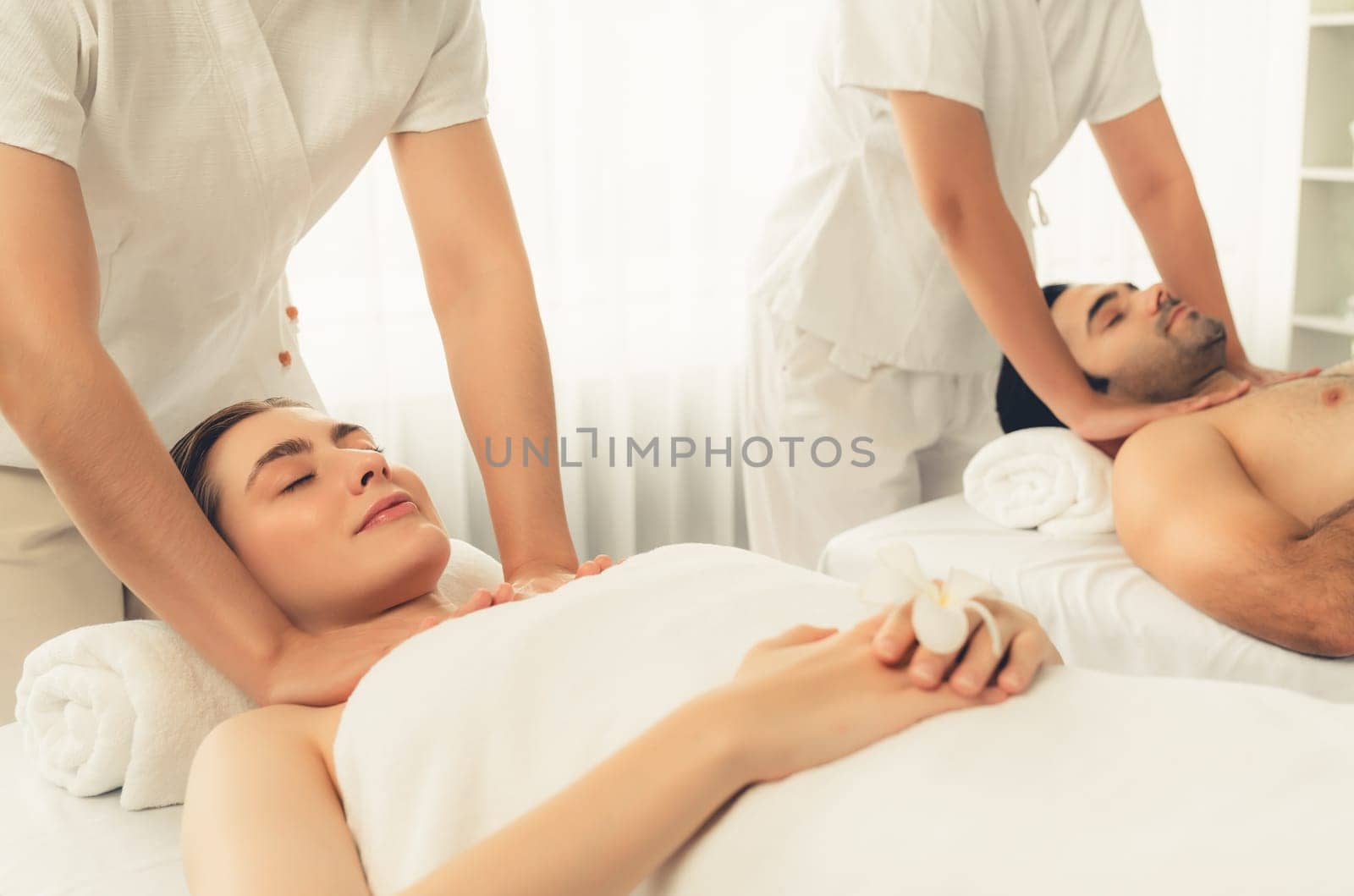 Caucasian couple customer enjoying relaxing anti-stress spa massage and pampering with beauty skin recreation leisure in day light ambient salon spa at luxury resort or hotel. Quiescent