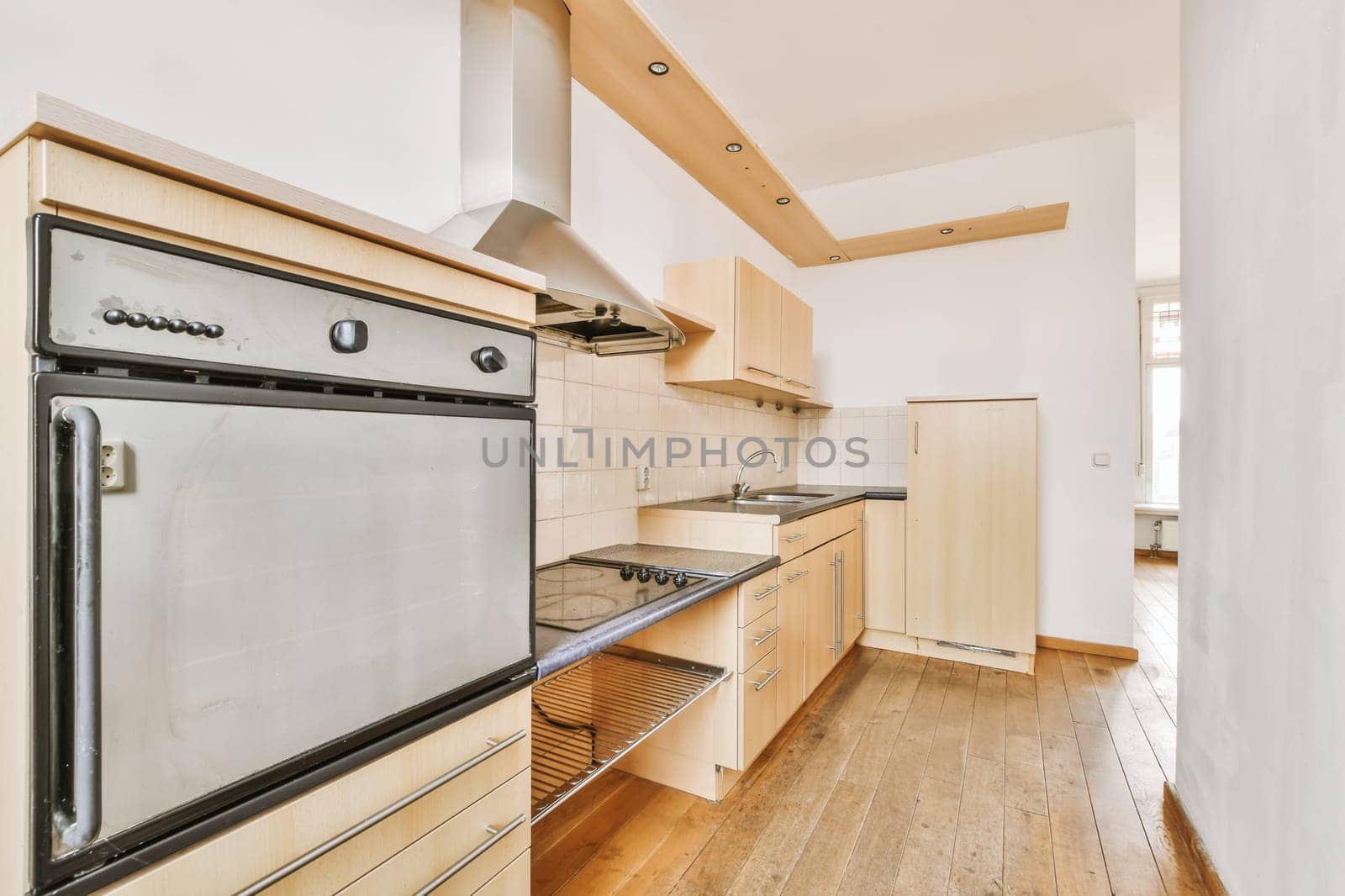 a kitchen with wood flooring and white walls, including an oven on the stove in the center of the room