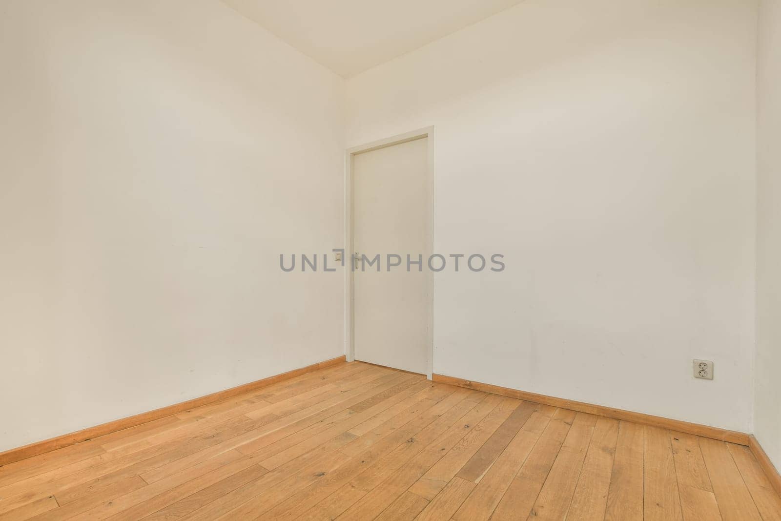 an empty room with white walls and wood flooring on the right, there is a door in the corner