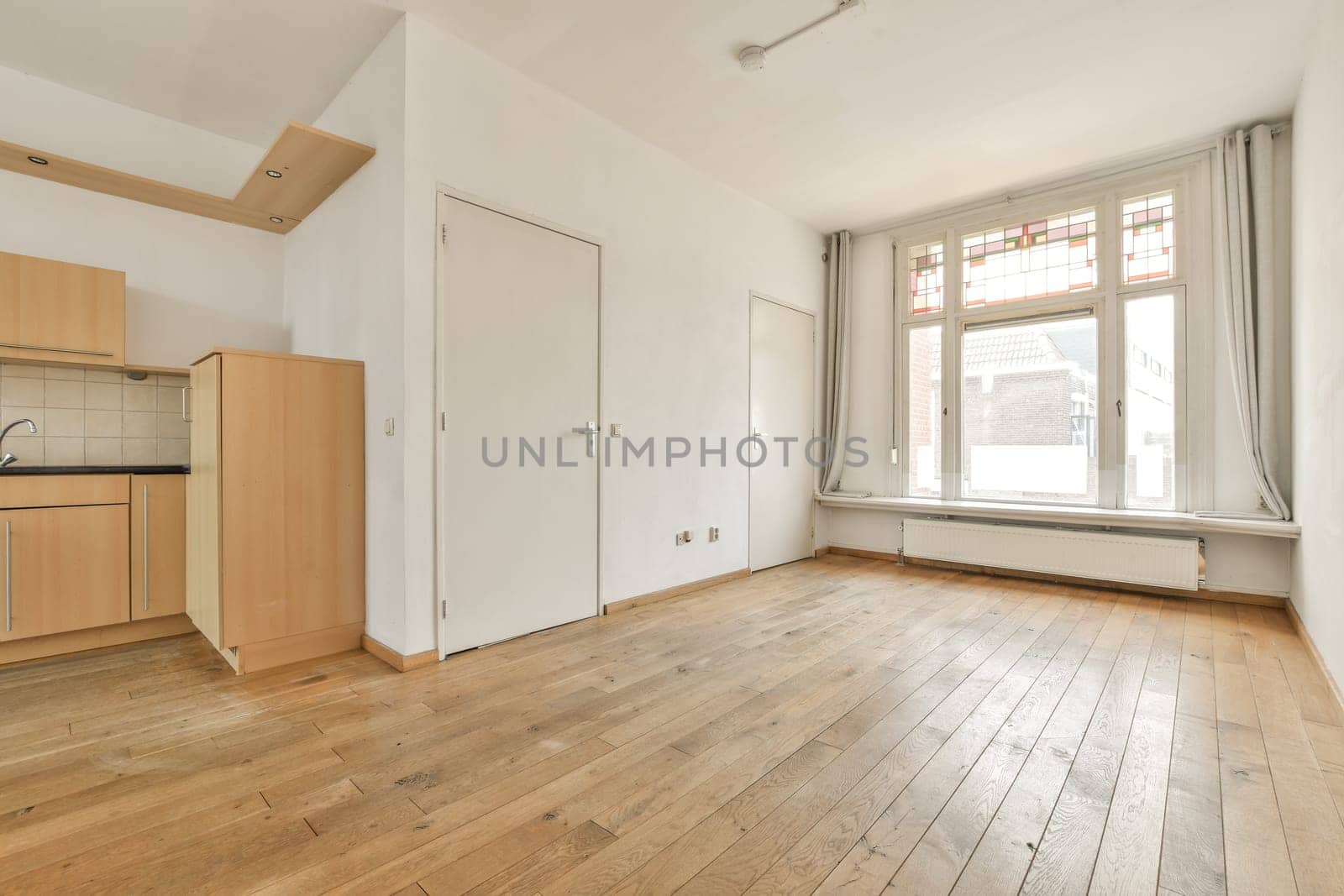 an empty living room with wood floors and a window by casamedia