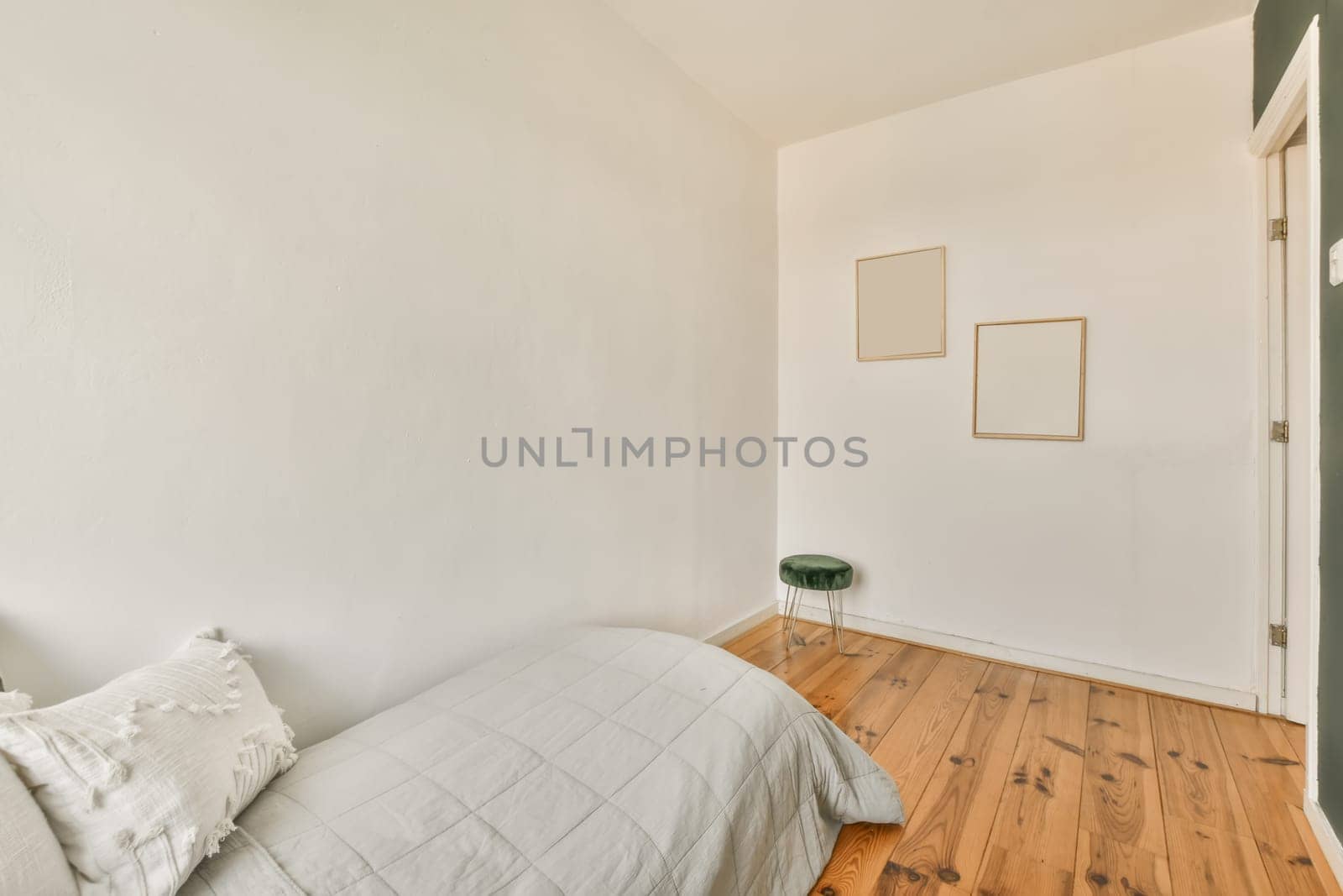 a bedroom with wood flooring and white walls, including a bed in the fore - image taken from above