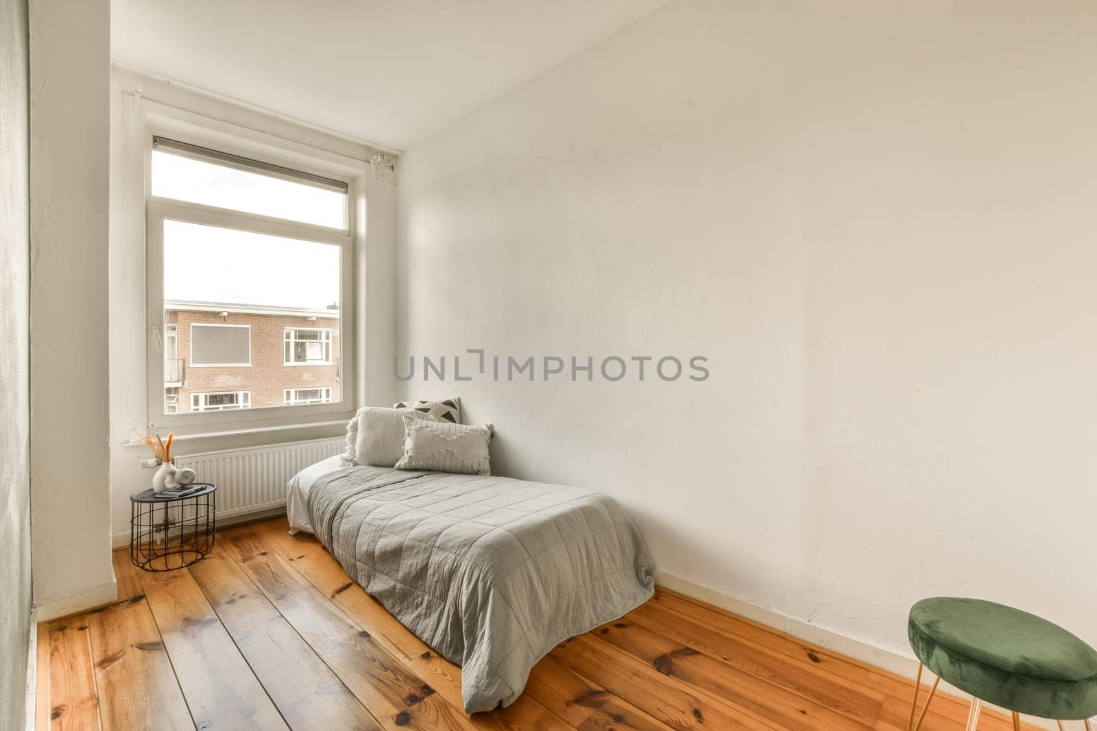 a bedroom with wood flooring and a bed in the corner, next to a window that looks out onto the street