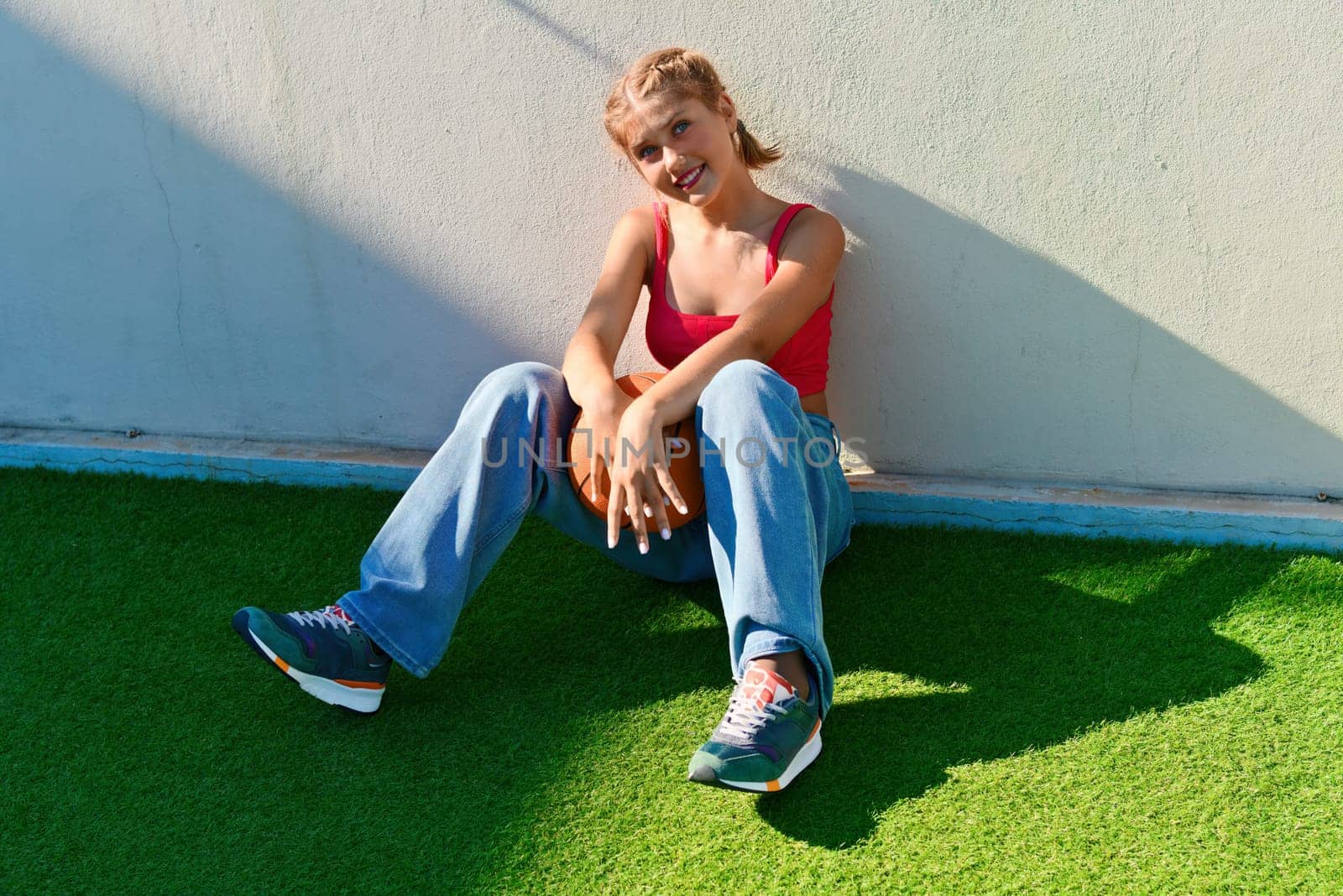 Cheerful teenage girl sitting on the sports ground.