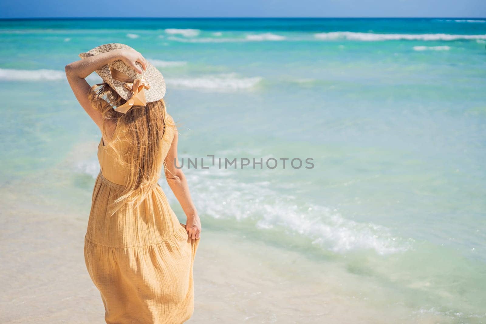 Radiant and expecting, a pregnant woman stands on a pristine snow-white tropical beach, celebrating the miracle of life against a backdrop of natural beauty.