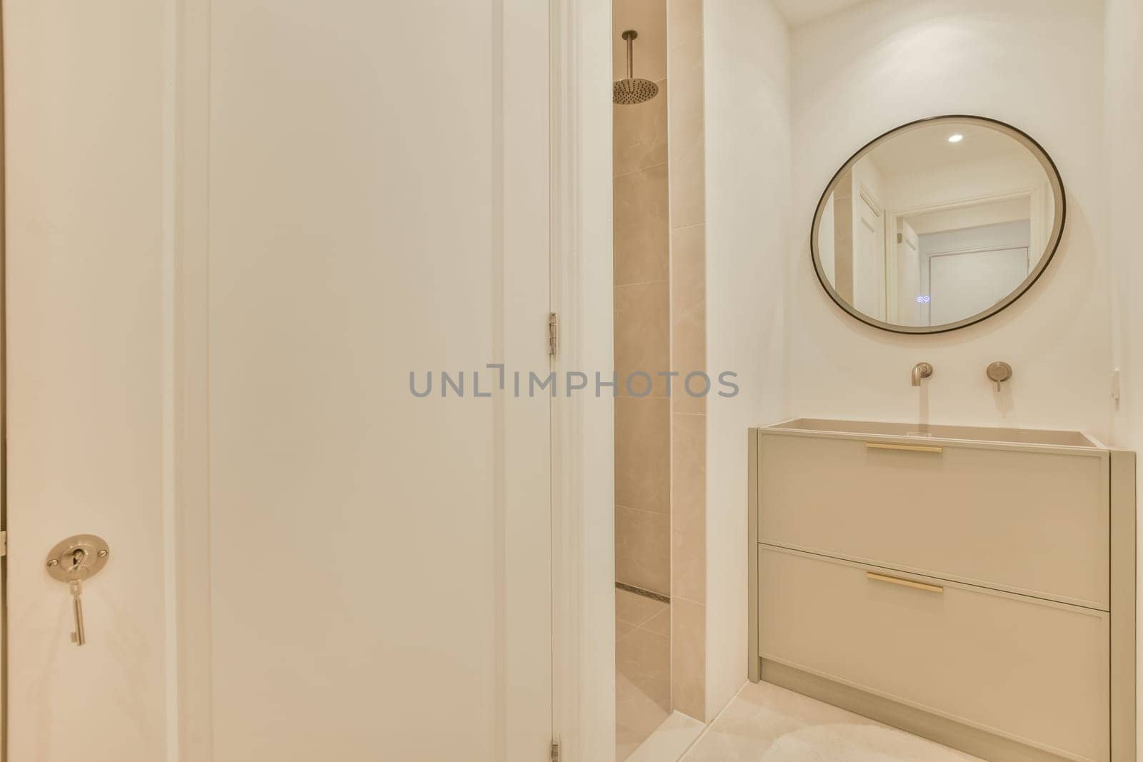 a bathroom with a mirror on the wall and white cupboards in front of the bathtub is next to the door