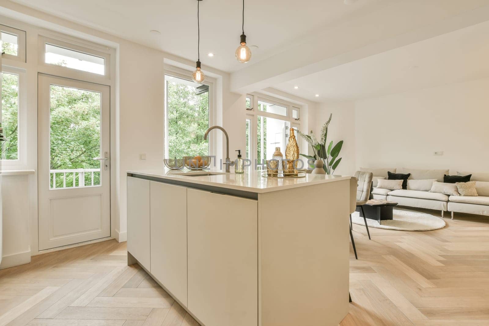 a kitchen and living room in a house with wood floors, white walls, hardwood flooring and large windows