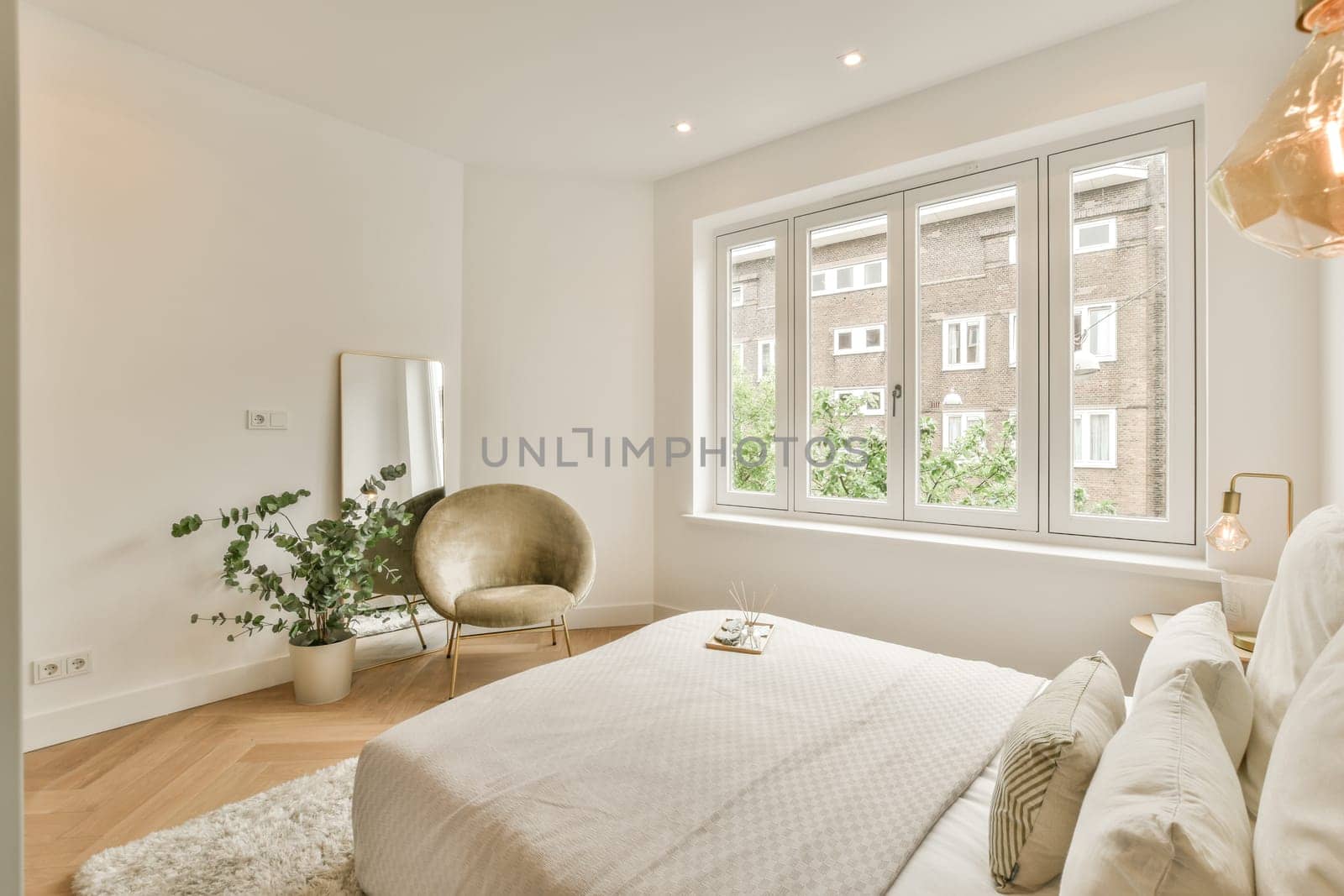 a bedroom with a bed, chair and lamp in front of the window that looks out onto an apartment block