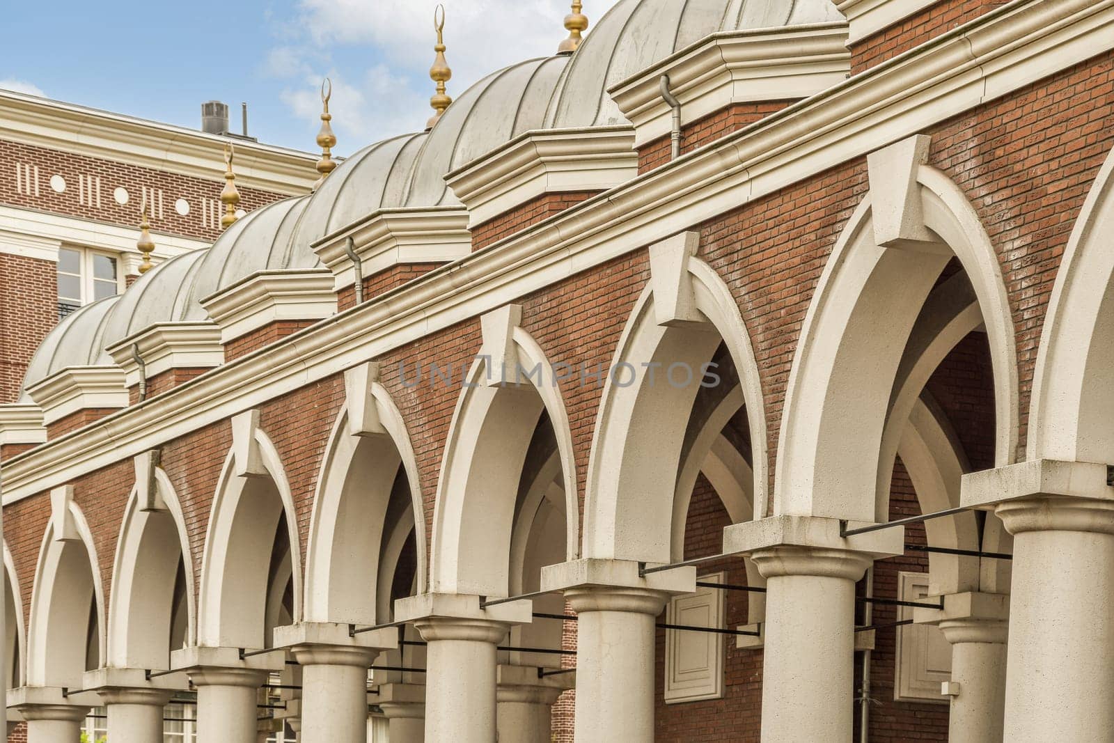 a brick building with arches on the front and an ornate clock at the top in the middle of the building