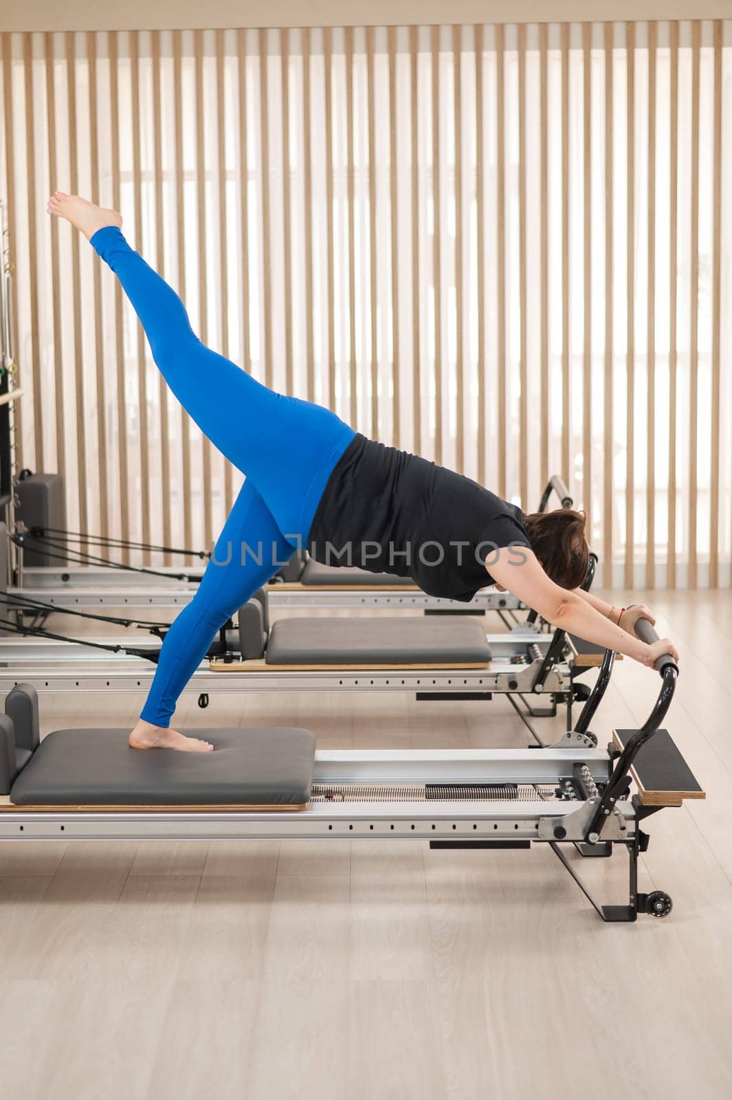 Overweight caucasian woman doing pilates exercises on a reformer