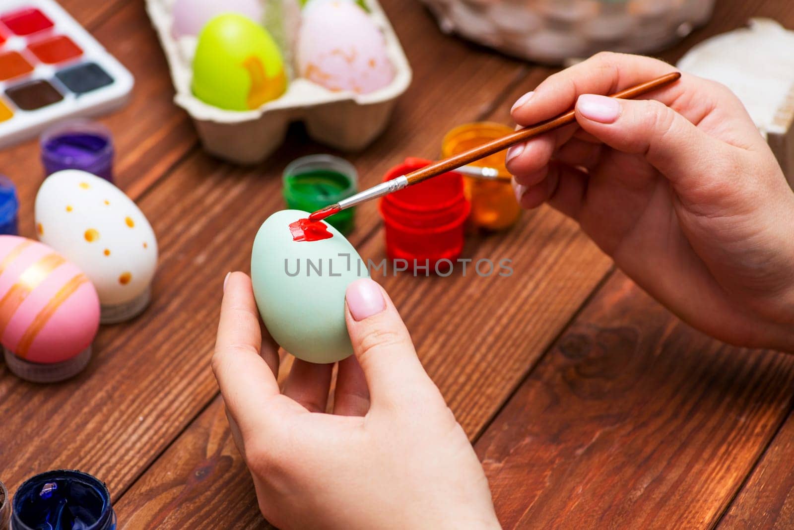 A woman with a tassel paints Easter eggs. Preparing decorations for Easter, creativity with children, traditional symbols. Preparing for Easter.