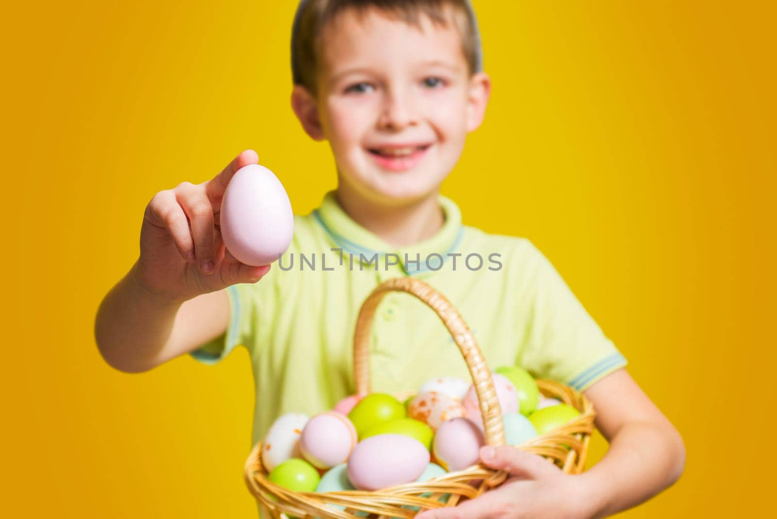 Cute little child is wearing bunny ears on Easter day and holding basket with painted eggs. Happy kid is holding Easter basket.