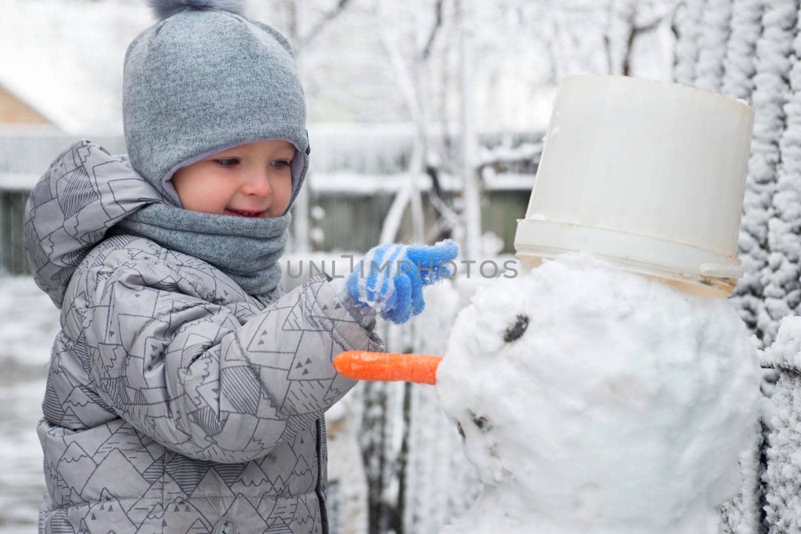 Cute little boy is making a snowman. Child playing with snow. Children wintertime outdoor activitie time concept.