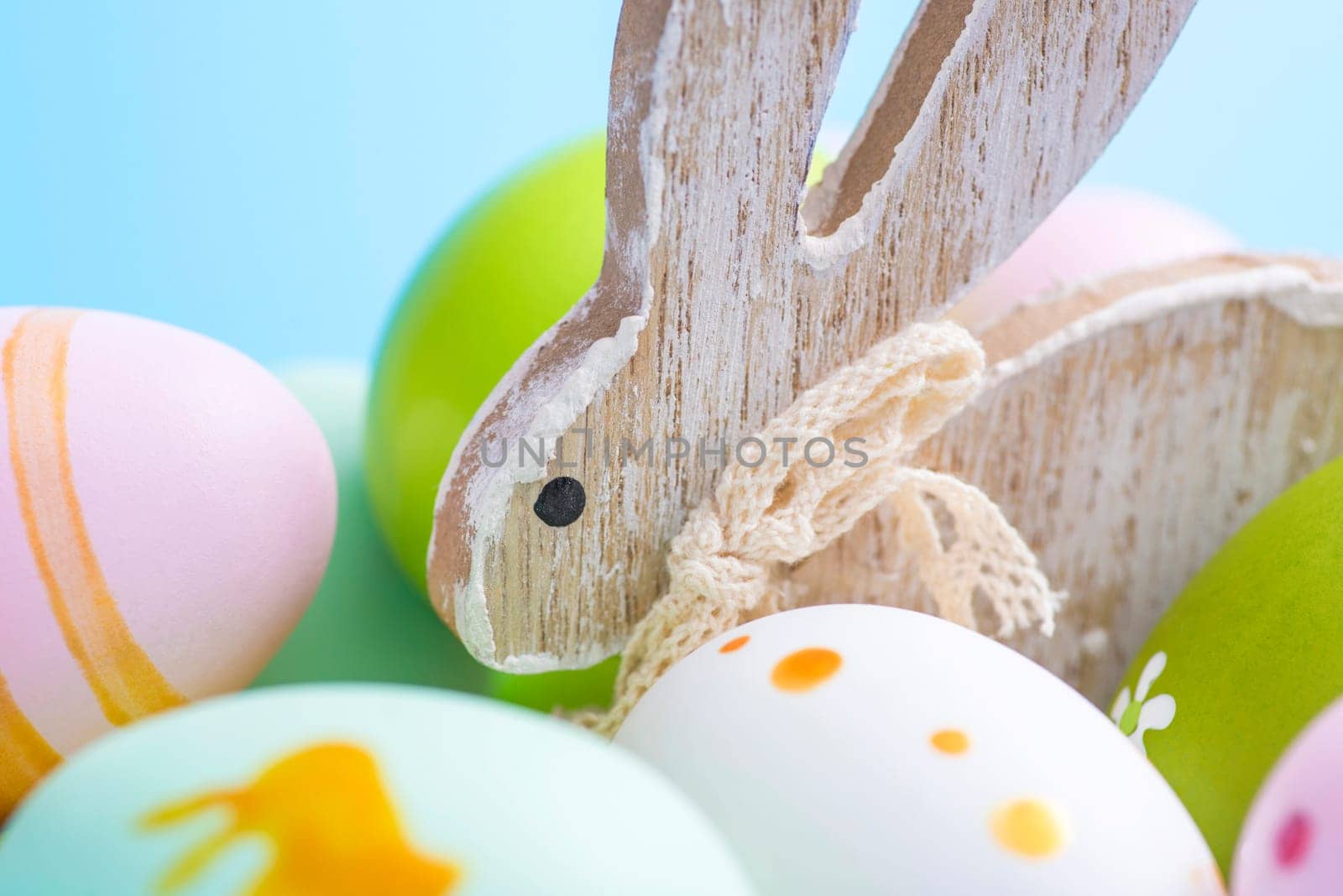 Colorful Easter eggs and wooden rabbit. Cute rabbit among Easter eggs.