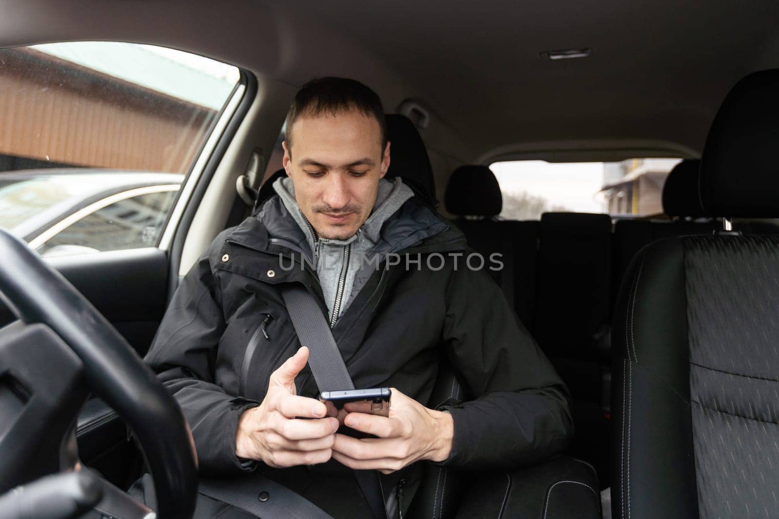 Success in motion. Handsome young man in full suit smiling while driving a car by Andelov13