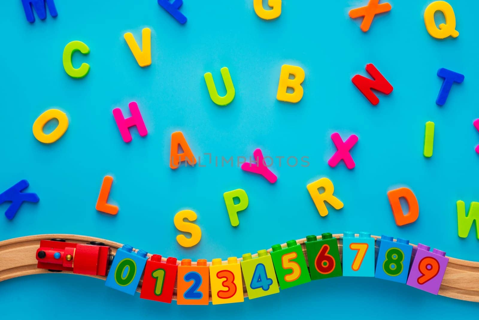 Educational toys blocks, numbers, letters, train on blue background. Toys for kindergarten, preschool or daycare. Early childhood education, learning to count, preschool and kids game concept. Top view.