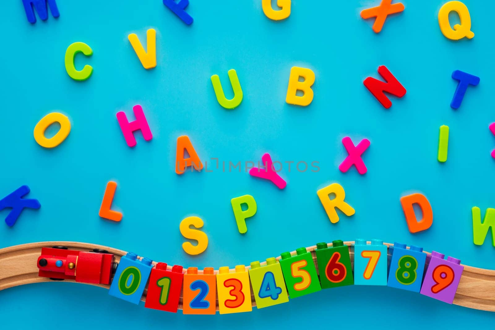 Educational toys blocks, numbers, letters, train on blue background. Toys for kindergarten, preschool or daycare. Early childhood education, learning to count, preschool and kids game concept. Top view.