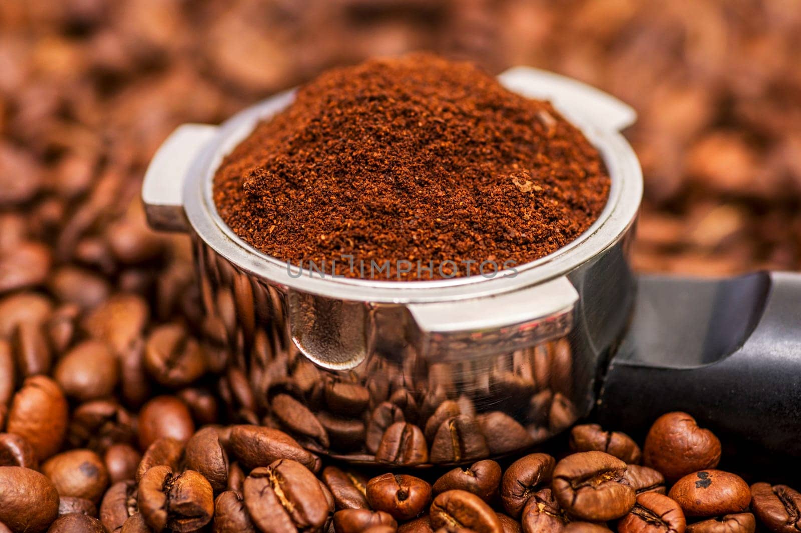 Freshly ground coffee in a metal filter on background coffee beans by andreyz