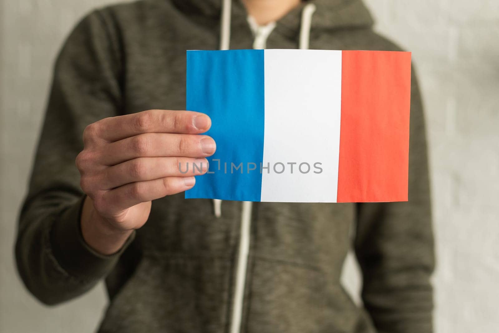 close up hand holding french flag on studio isolated white background.