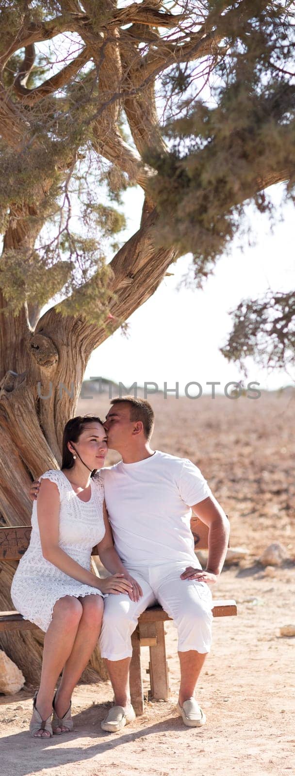 happy young couple kissing and hugging, sitting under the tree