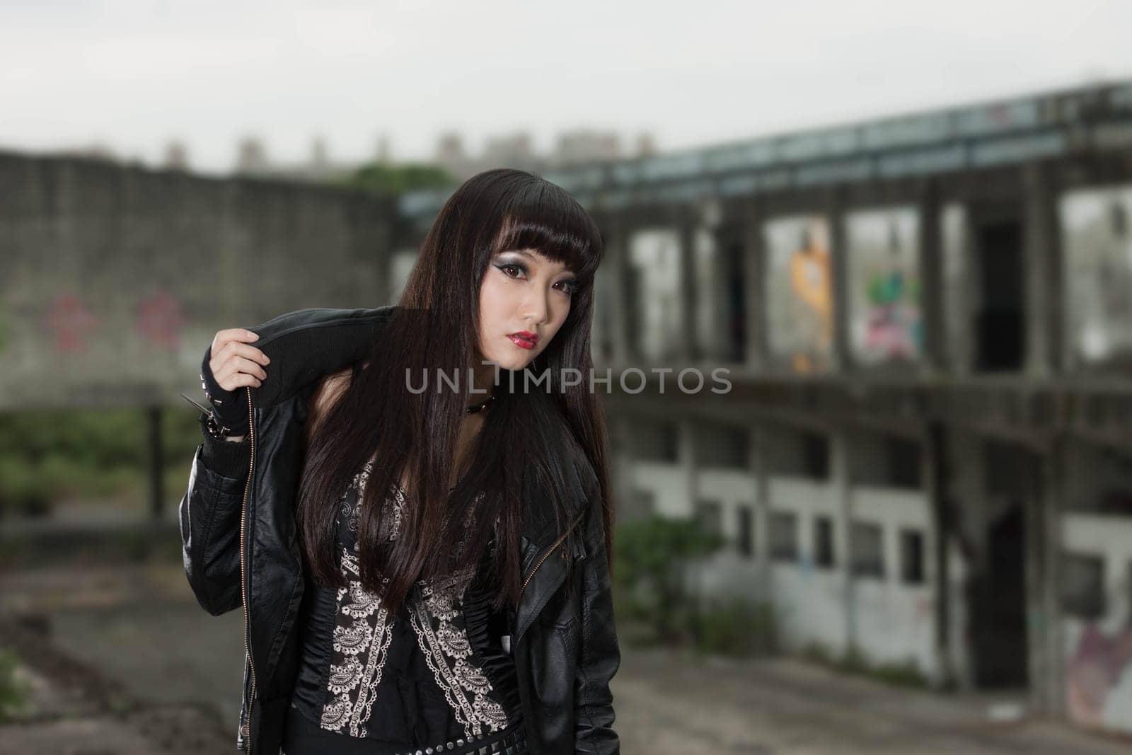 Asian American woman in emo goth clothing at an abandoned building