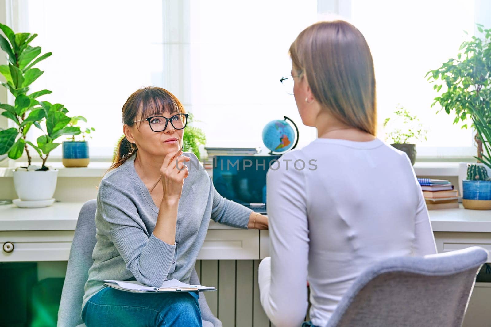 Female psychologist therapist working with young teen girl sitting in office. Teenage female student at therapy meeting with counselor. Psychology therapy psychotherapy youth mental health treatment