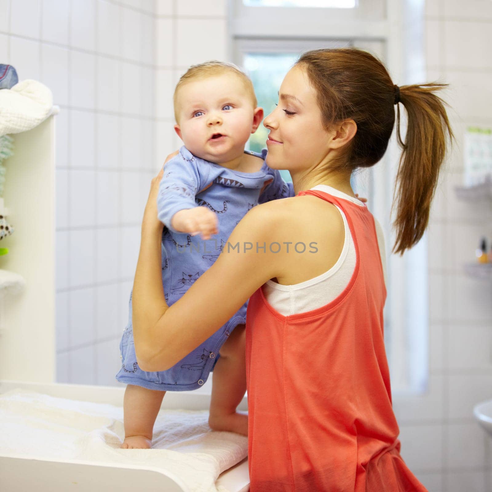 Mother, holding and baby for change of clothes in nursery on table. Young woman, infant or little boy with embrace, love and caring for development, growth or comfort in morning, together and bond.