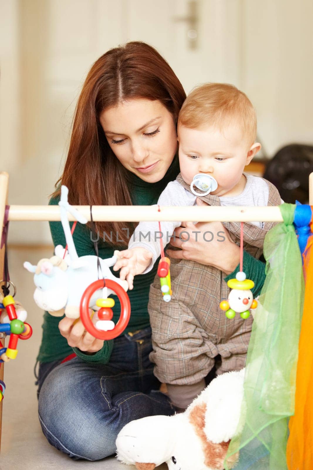 Mother, baby and playing with toys in living room for childhood development in home. Woman, son and hold with pacifier for care, love and support in bonding, together and future growth with games by YuriArcurs