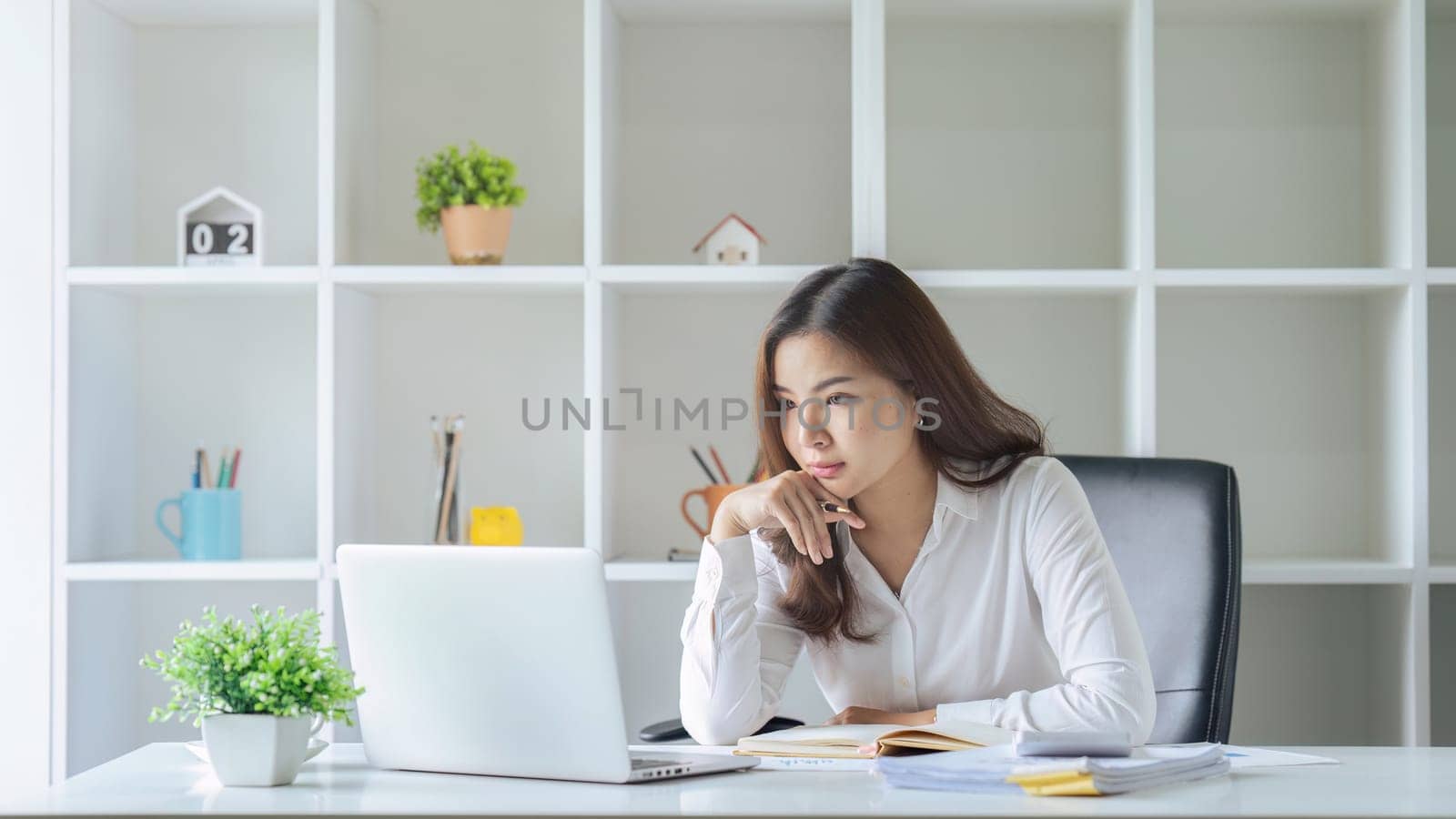 Asian Businesswoman sitting at her desk and busy working on a laptop in office by itchaznong