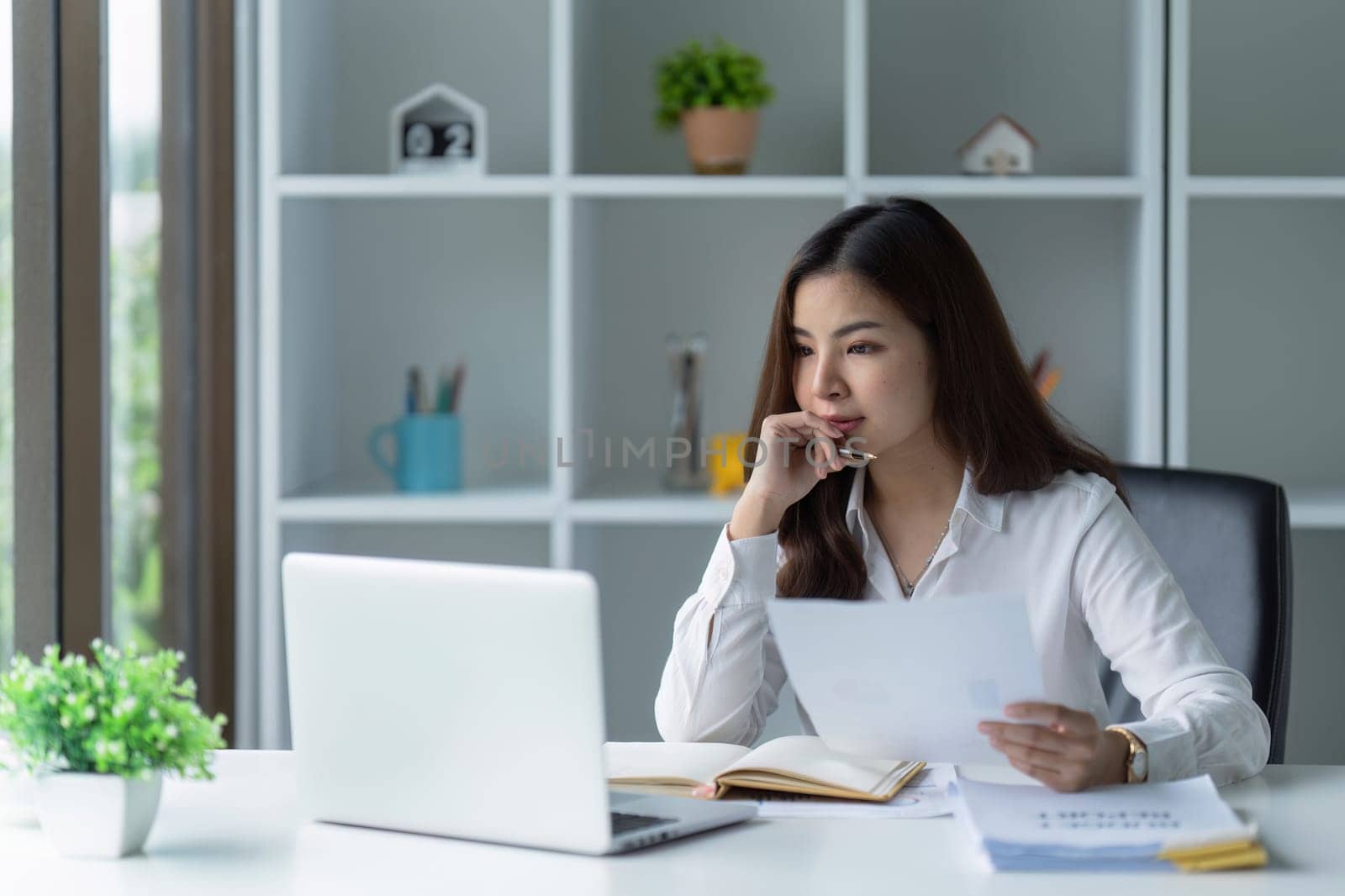 Asian Businesswoman sitting at her desk and busy working on a laptop in office.