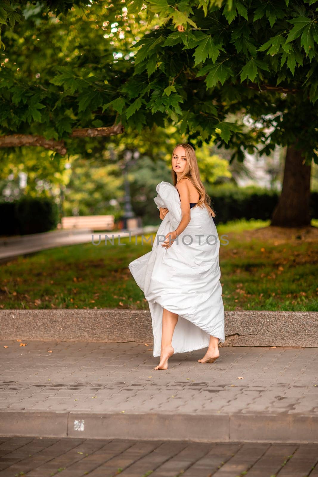 Woman city blanket. Morning in the big city. A blonde woman in a white blanket is enjoying in the city center. Photographed for social media.