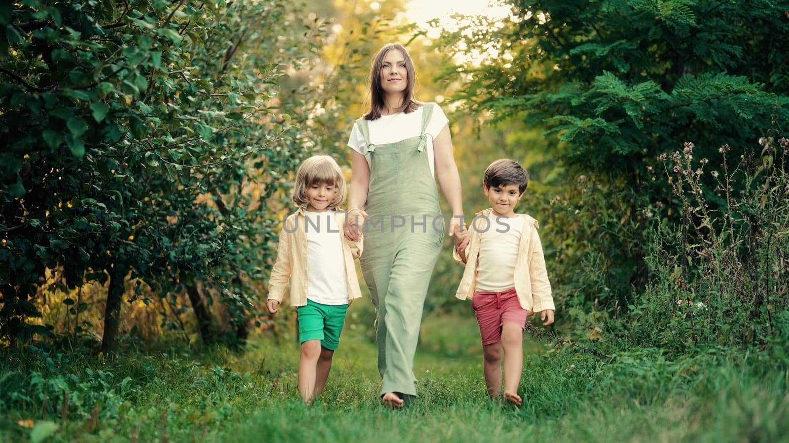 Young family - mom and two brothers twins boys walking in green park or garden. Happy mother and children, love, freedom, future, home, countryside concept