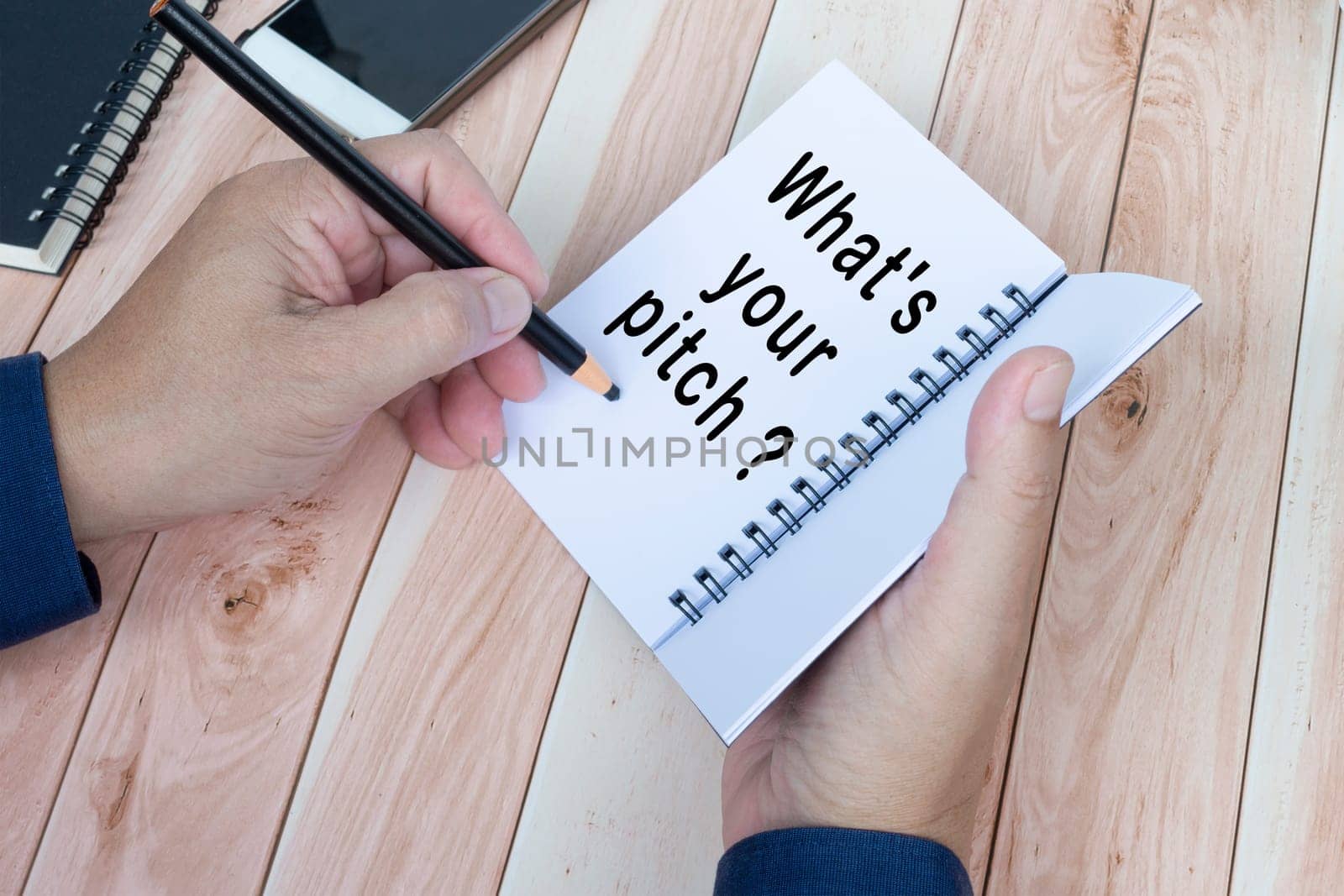 Businessman hands with pen writing notebook on office desk. What's your pitch. Business concept.