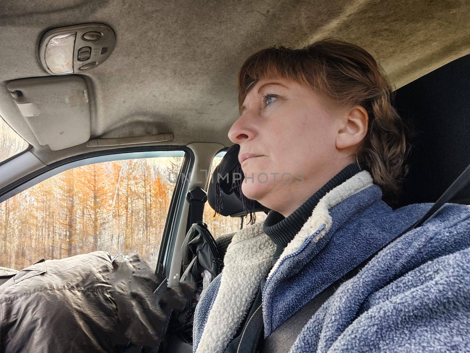 Portrait of female driver in solo journey. Adult mature woman holding steering wheel and looking through windscreen in travel by vehicle on vacation. Lady girl who is owner or rent car for travel