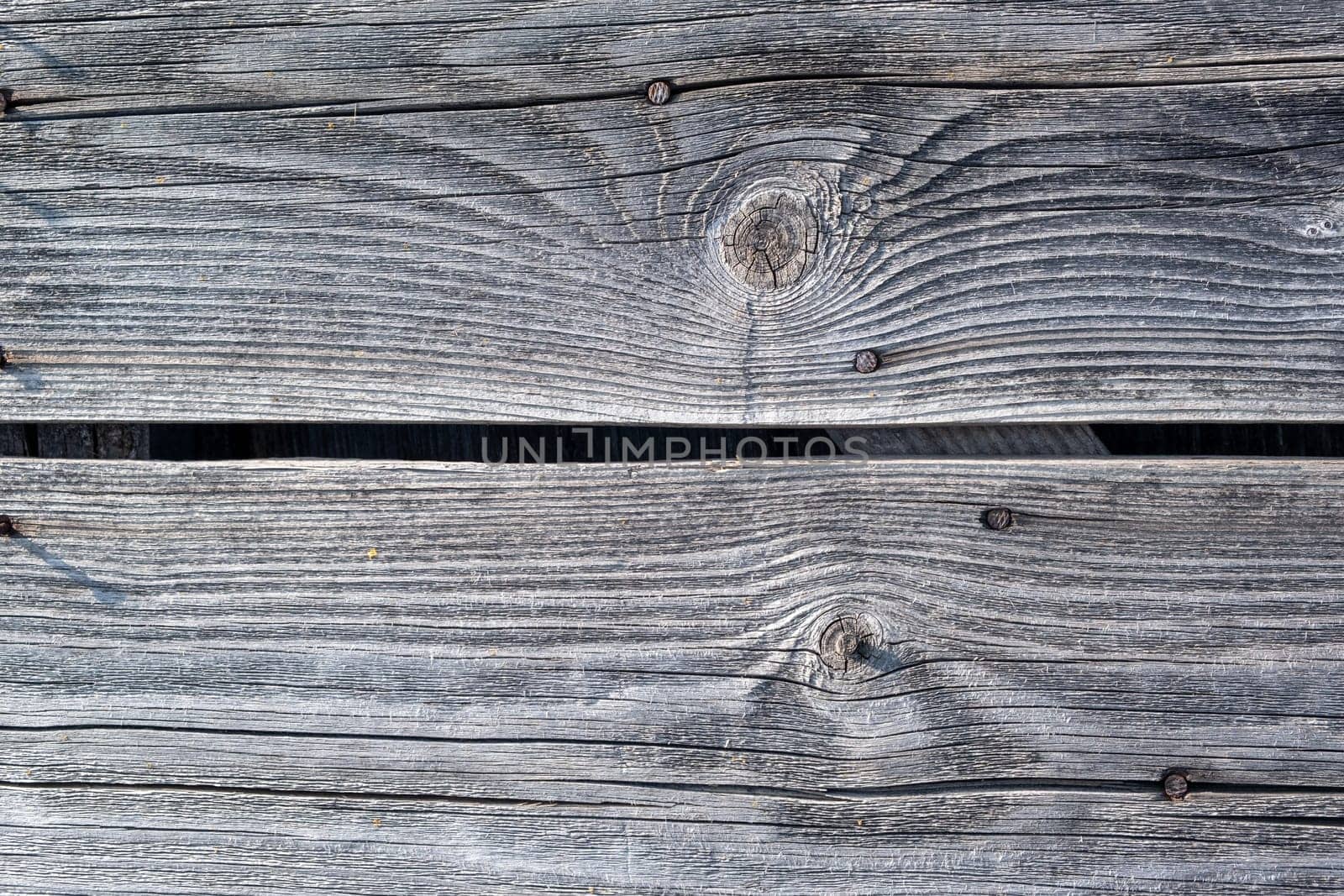 Elements of the walls of a wooden old village house. Wooden Log cabin walls texture. Weathered surface of an old wooden log house close-up. Old wooden log building in winter close-up.