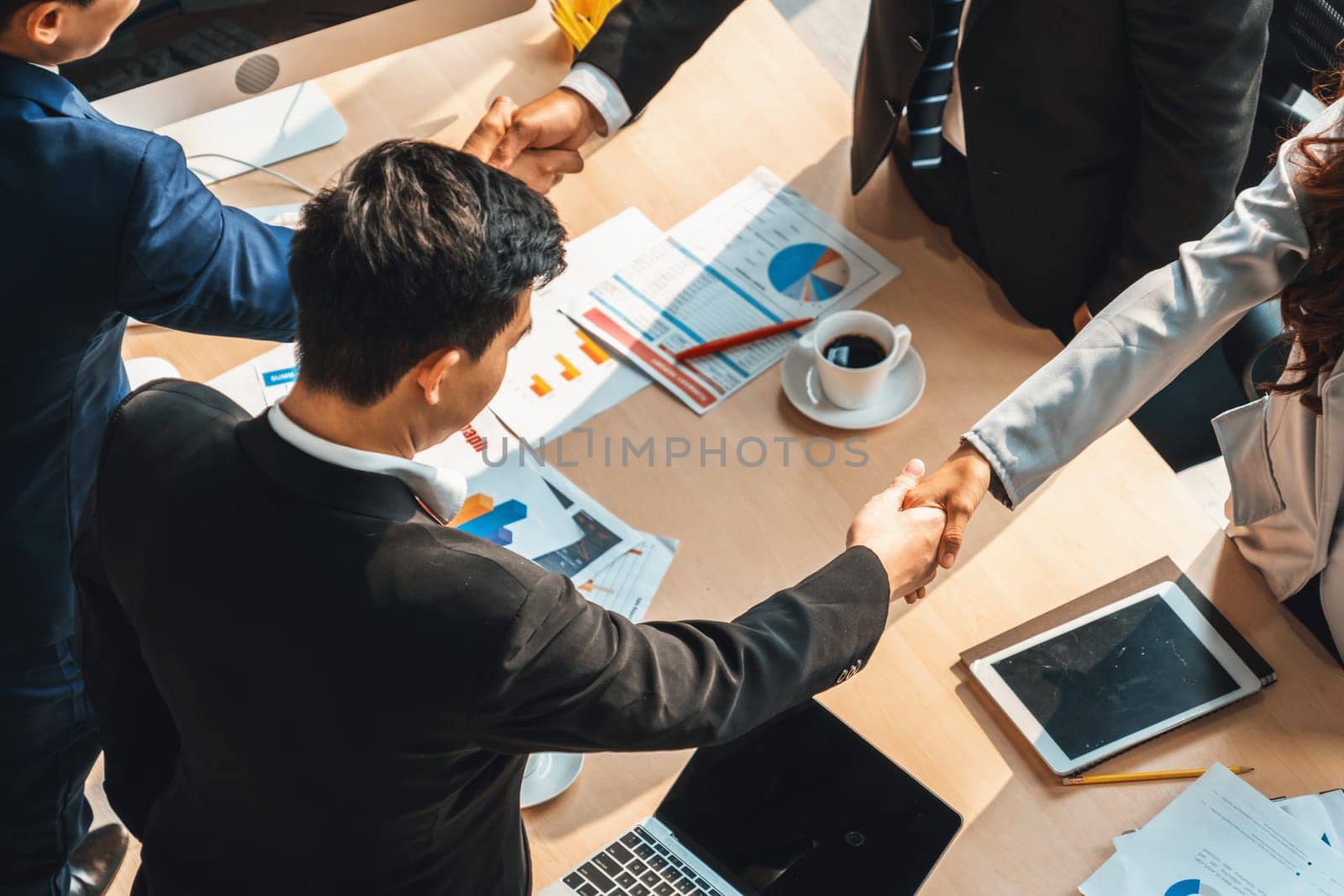 Group business people handshake at meeting table in office together with confident shot from top view . Young businessman and businesswoman workers express agreement of investment deal. Jivy