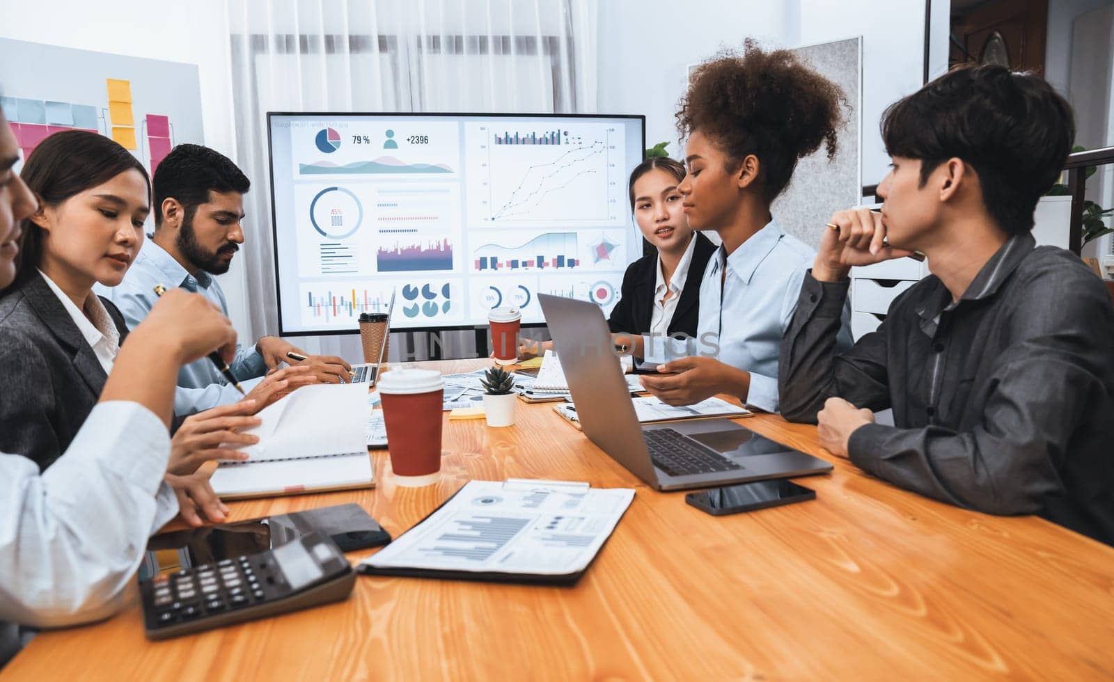 Multiracial analyst team use BI dashboard data to analyze financial report on meeting table. Group of diverse business people utilize data analysis by FIntech for business marketing decision. Concord