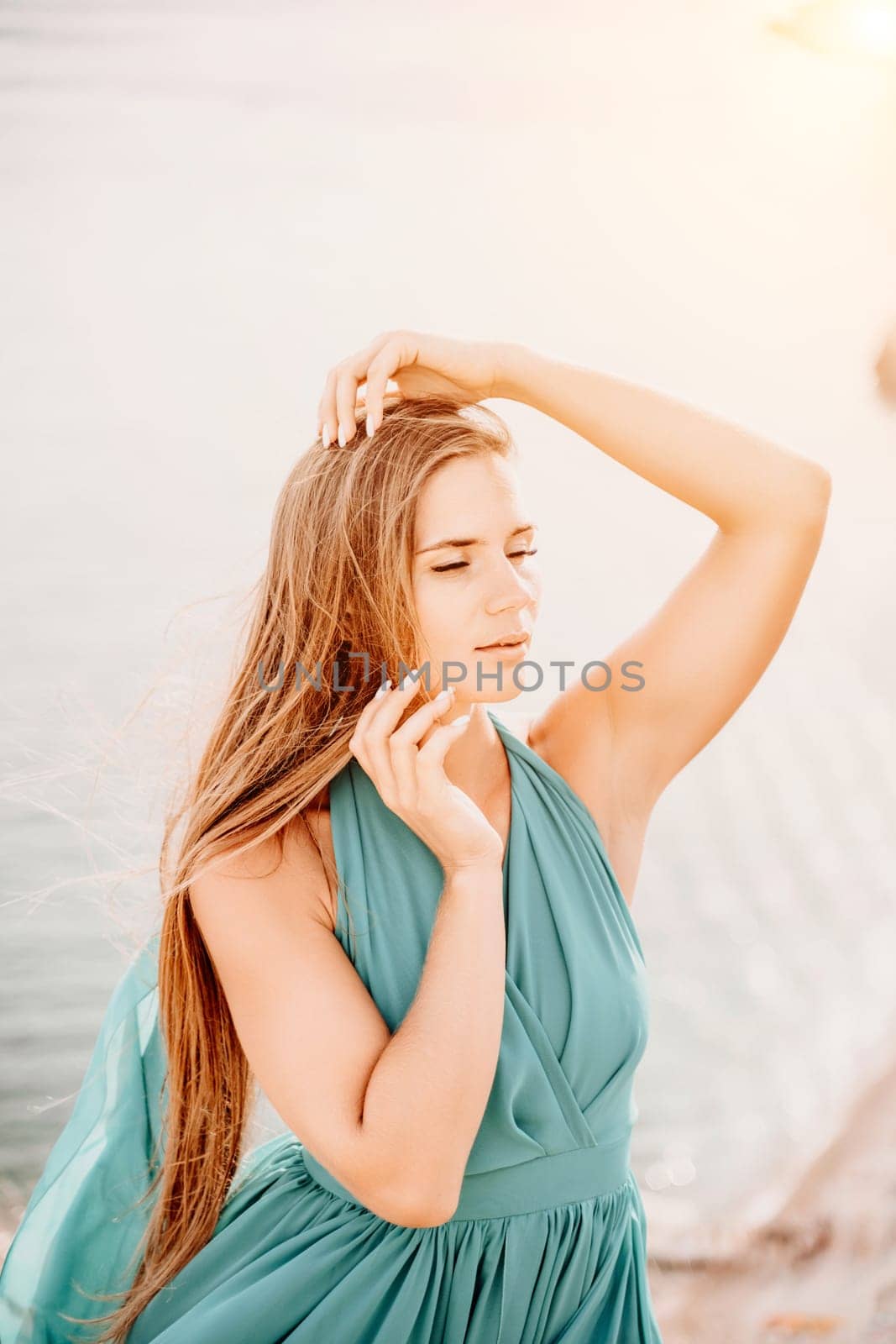 Woman sea green dress. Portrait of a happy woman with long hair in a long mint dress posing on a beach with calm sea bokeh lights on sunny day. Girl on the nature on blue sky background