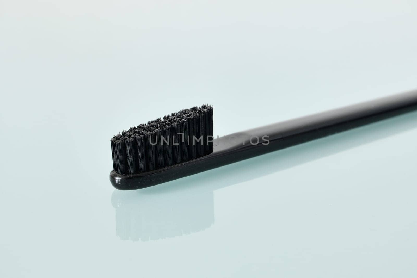 Black Toothbrush on a light blue background by olgavolodina