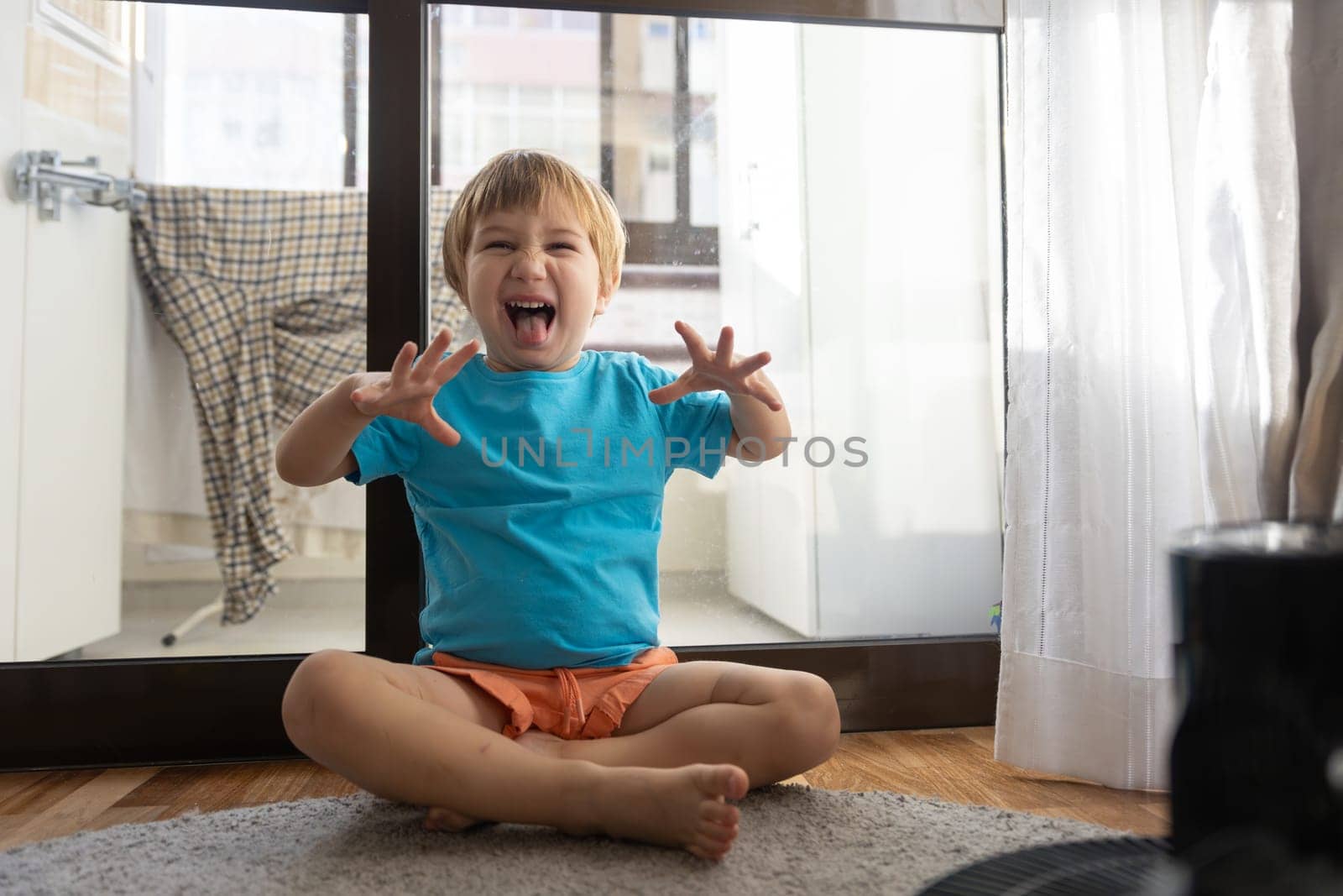 A little boy sitting on the floor with his hands in the air