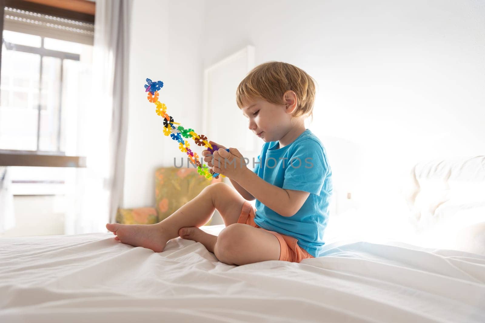 Little boy plays with toys on bed by Studia72