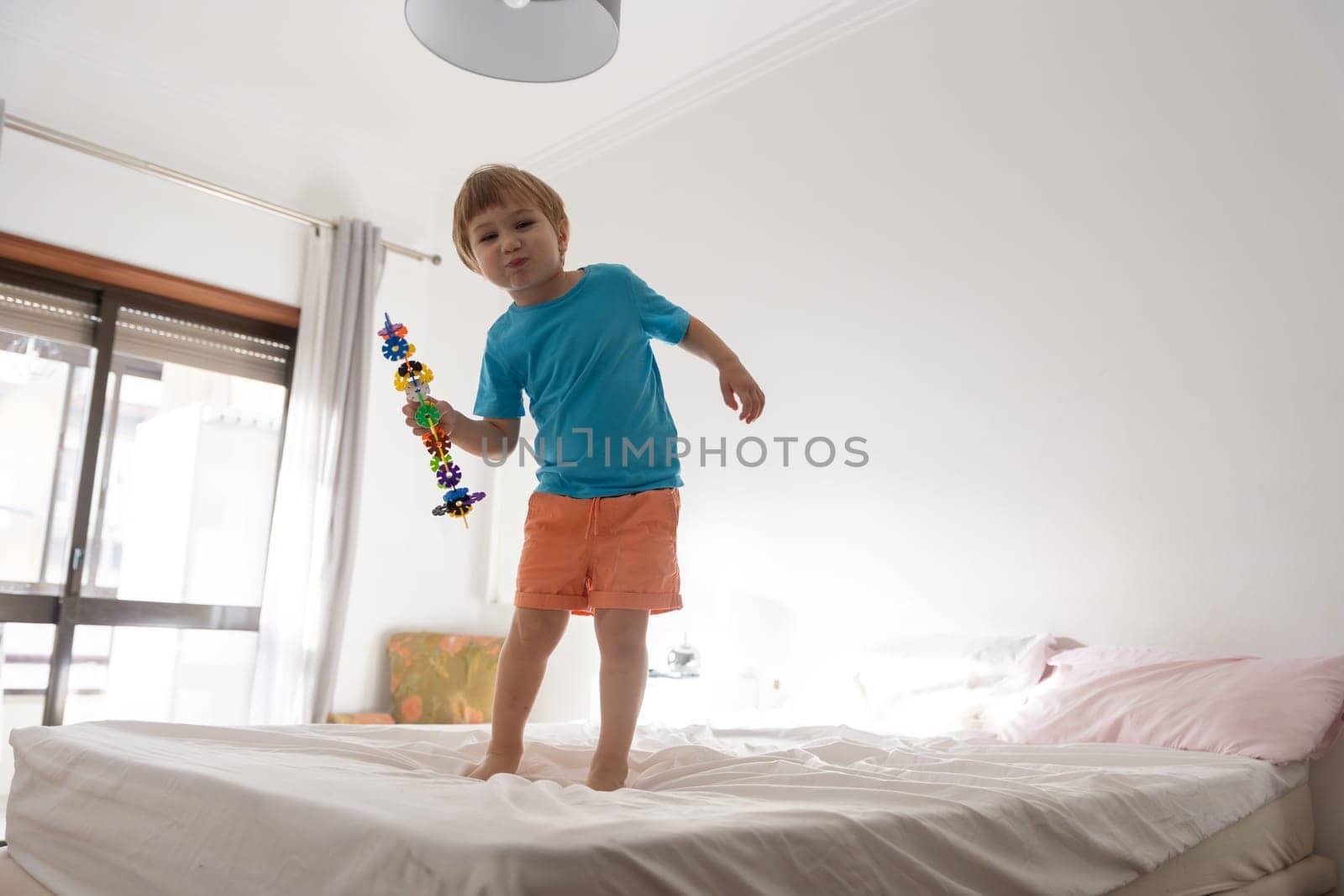 A young boy standing on top of a bed
