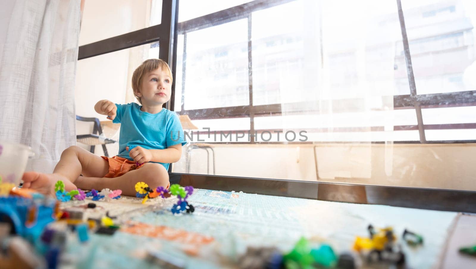 A little boy sitting on a chair in front of a window