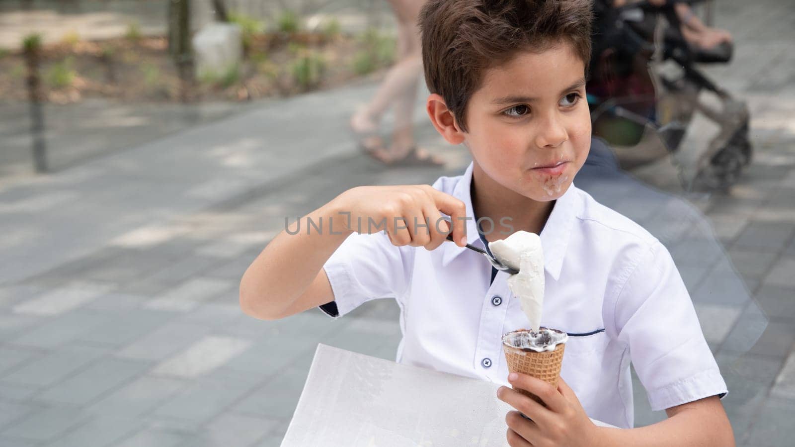 Cute child boy with a dirty face eats ice cream, the child enjoys dessert on a walk in the park, High quality photo
