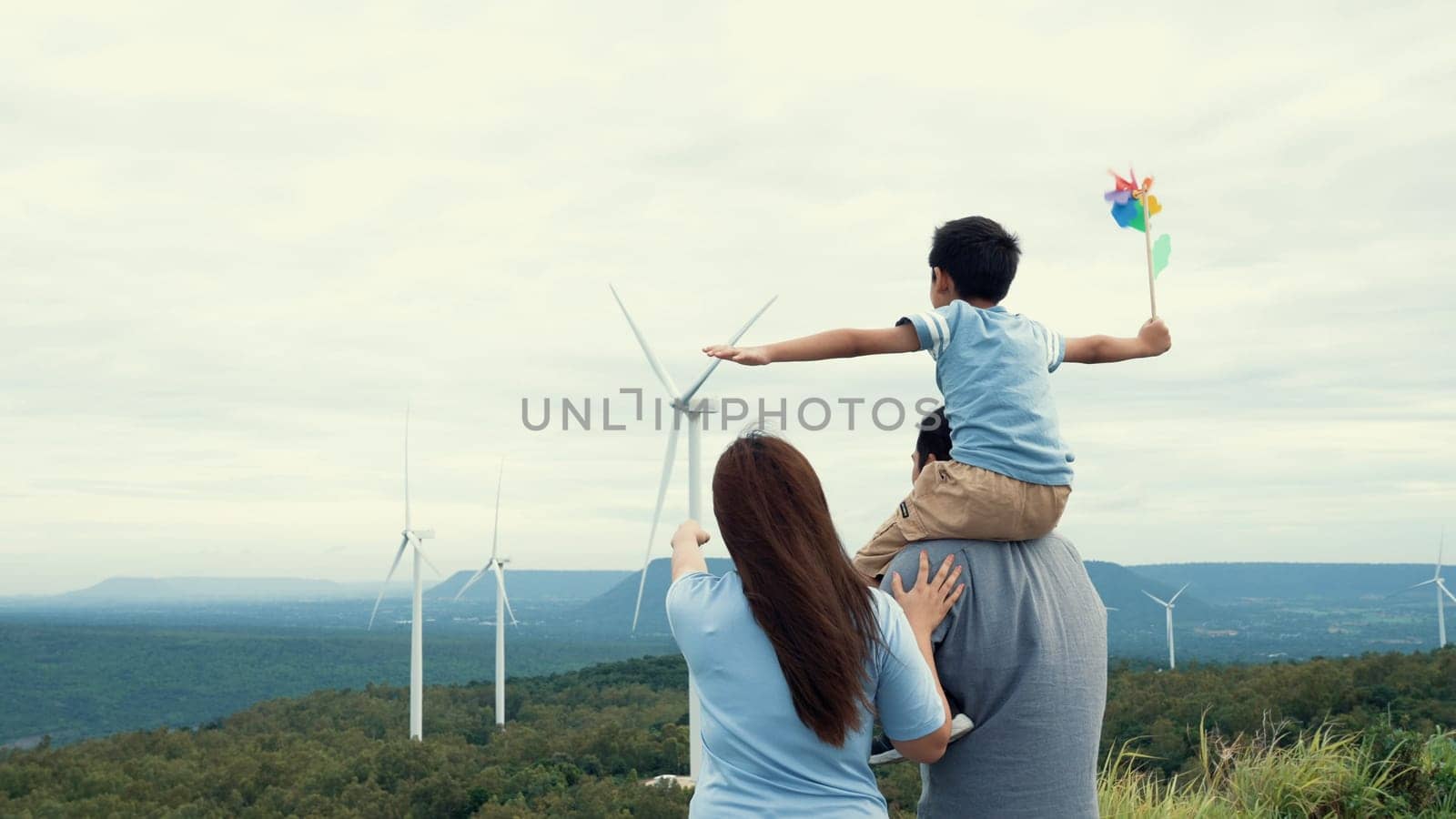 Concept of progressive happy family enjoying their time at the wind turbine farm by biancoblue