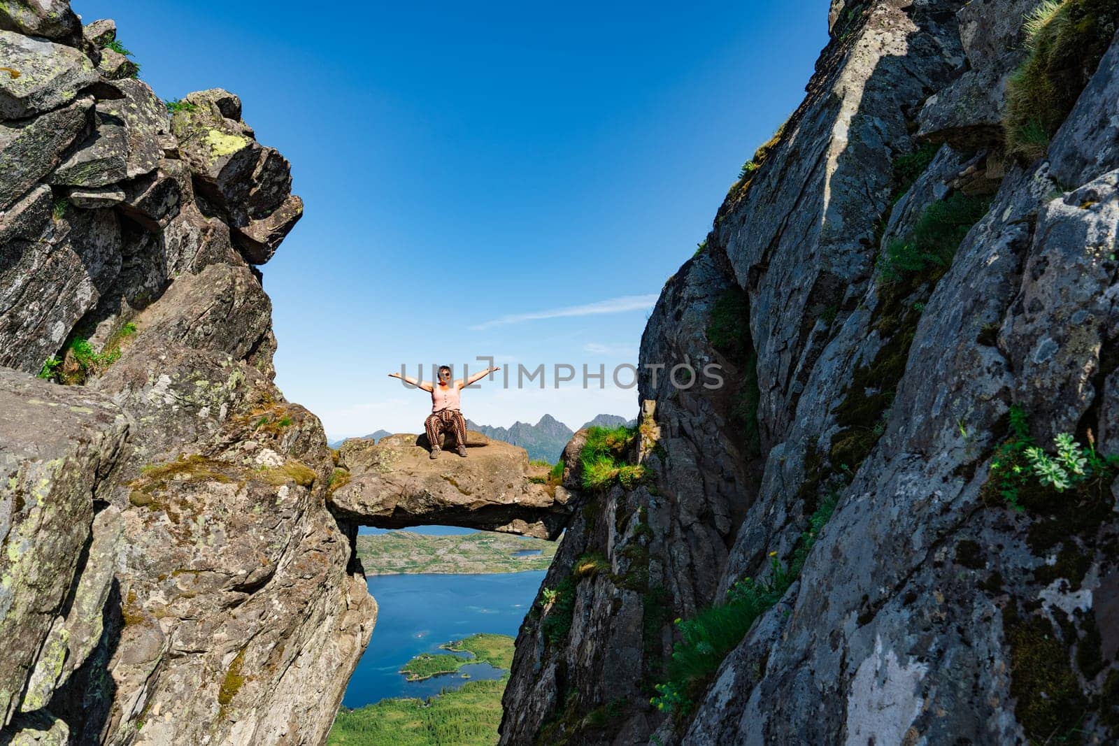 Active Senior tourist woman hiking at the beautiful Rock stuck in mountains Djevelporten. Norway. Happy pensioner climbing a mountain. Scandinavian tourism. Enjoying the outdoor leisure activity lifestyle