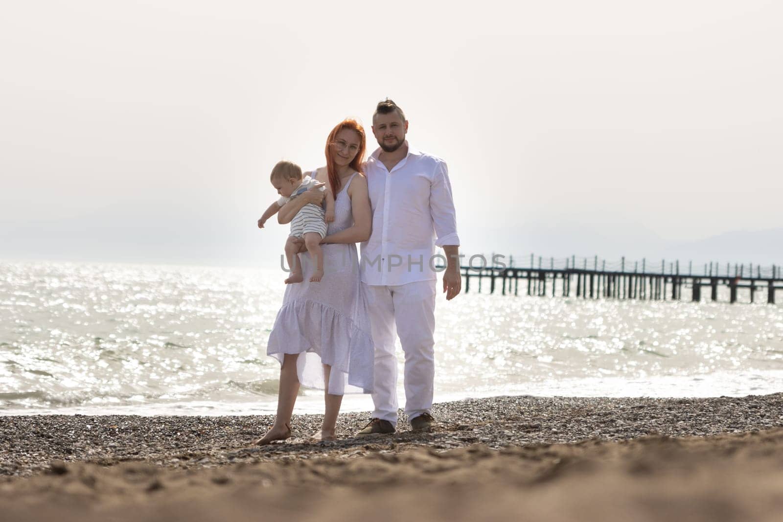 Happy family on vacation - standing on the beach with little baby son by Studia72
