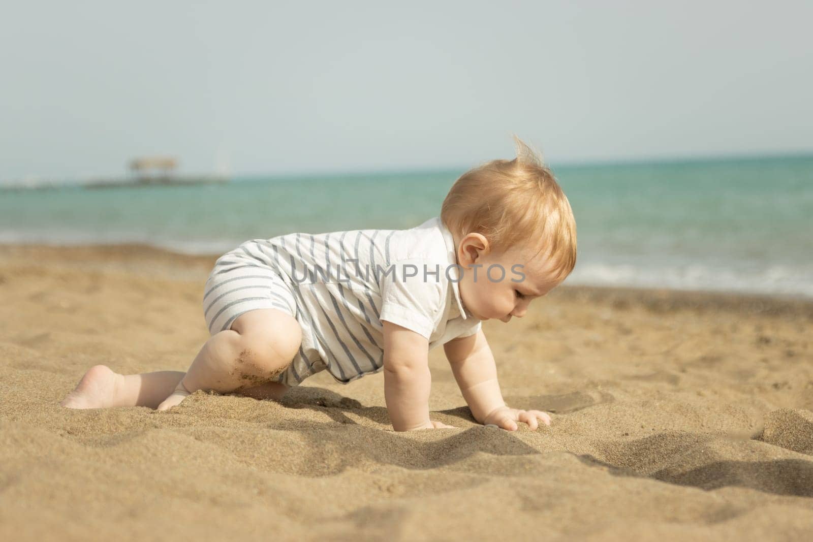 A baby boy crawling on a sand on the seaside by Studia72