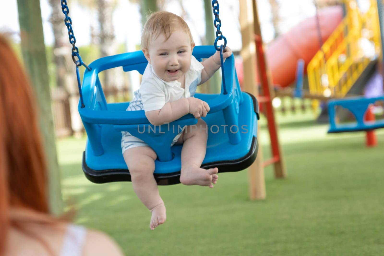 A little funny boy on swings on an outside playground. Mid shot