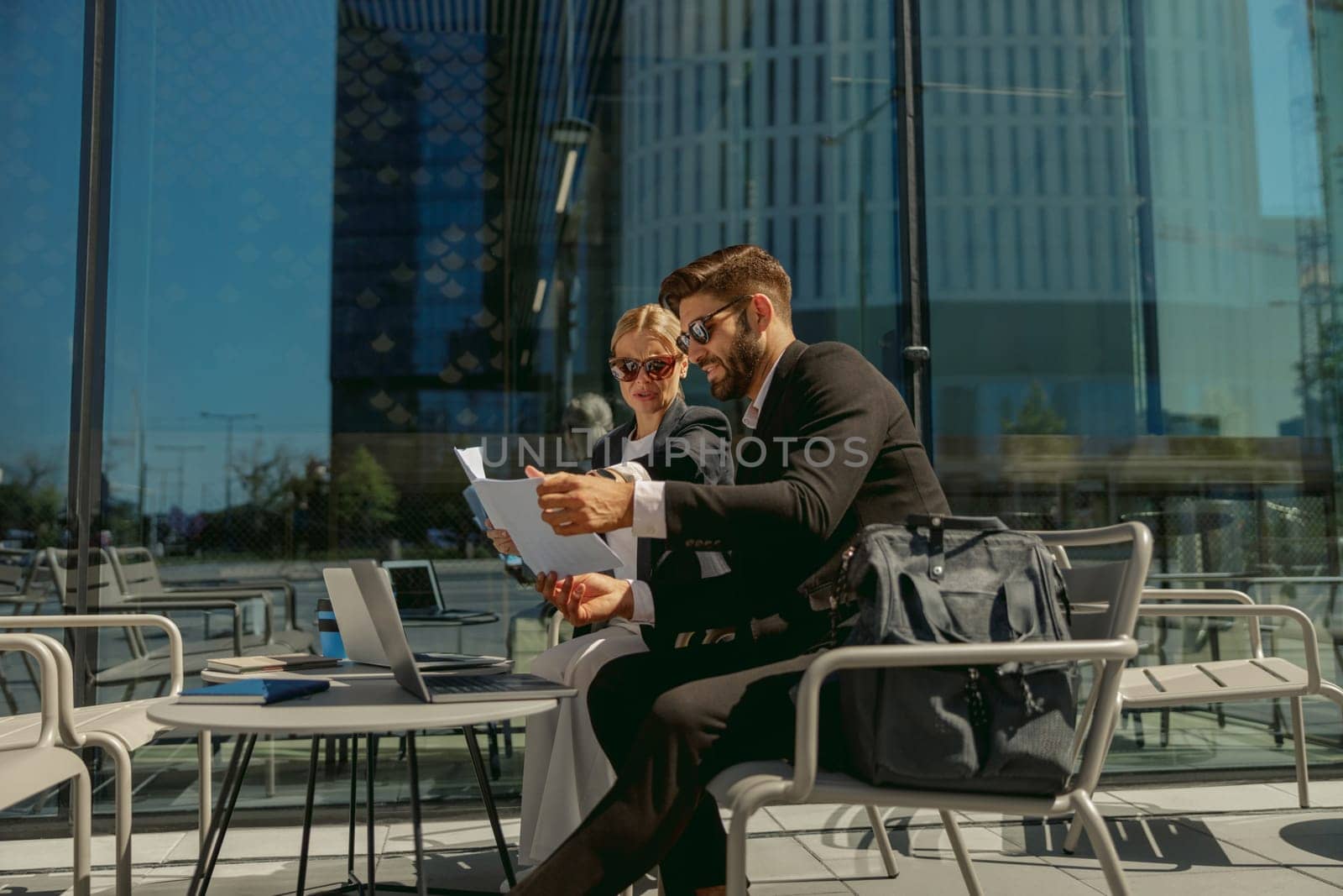 Business colleagues working with documents sitting outside of office on cafe terrace